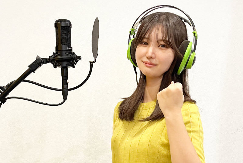 マイクの前でガッツポーズをするヘッドフォンをつけた女性