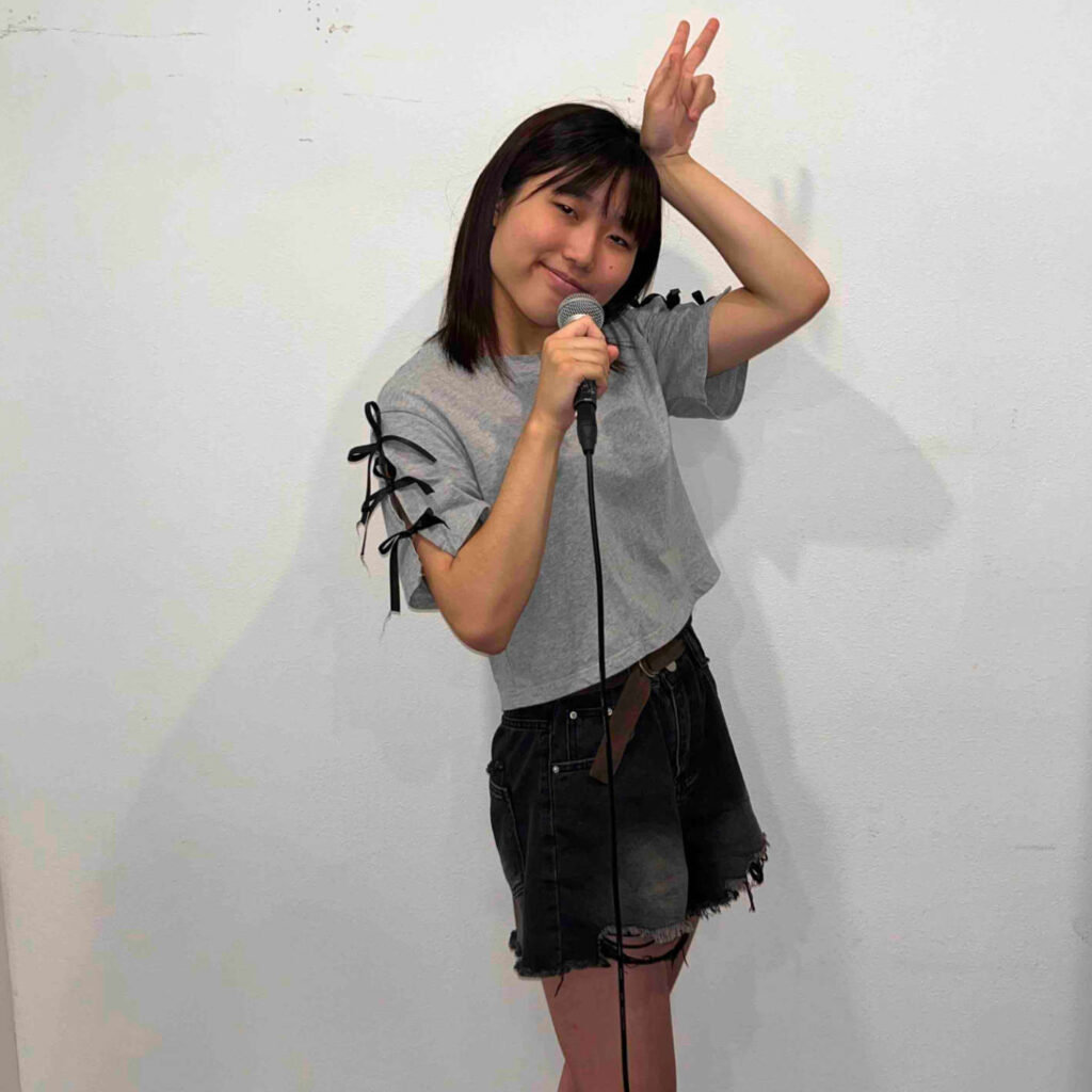 マイクを持ってピースをしながら歌う少女