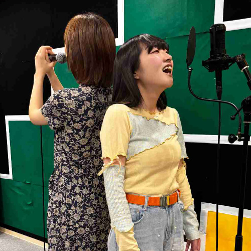 背中合わせで歌う2人の女性